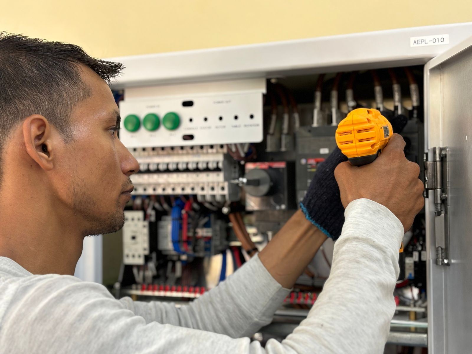 A technician working inside an electrical distribution panel